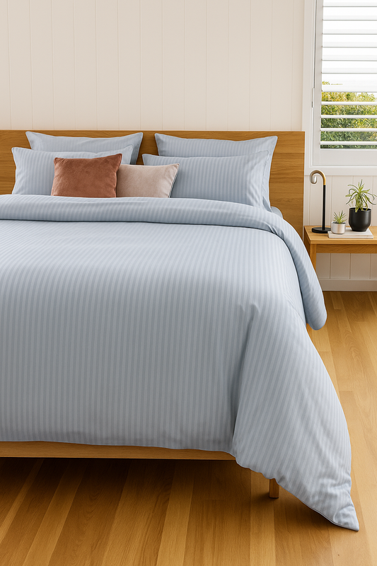 Bedroom with a neatly made bed featuring light blue bedding and pillows.